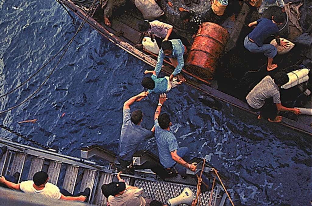 South China Sea....Crewmen of the amphibious cargo ship USS Durham (LKA-114) take Vietnamese refugees aboard a small craft.