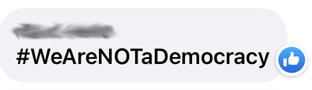 Screenshot of a Facebook reply that say "#WeAreNOTaDemocracy"