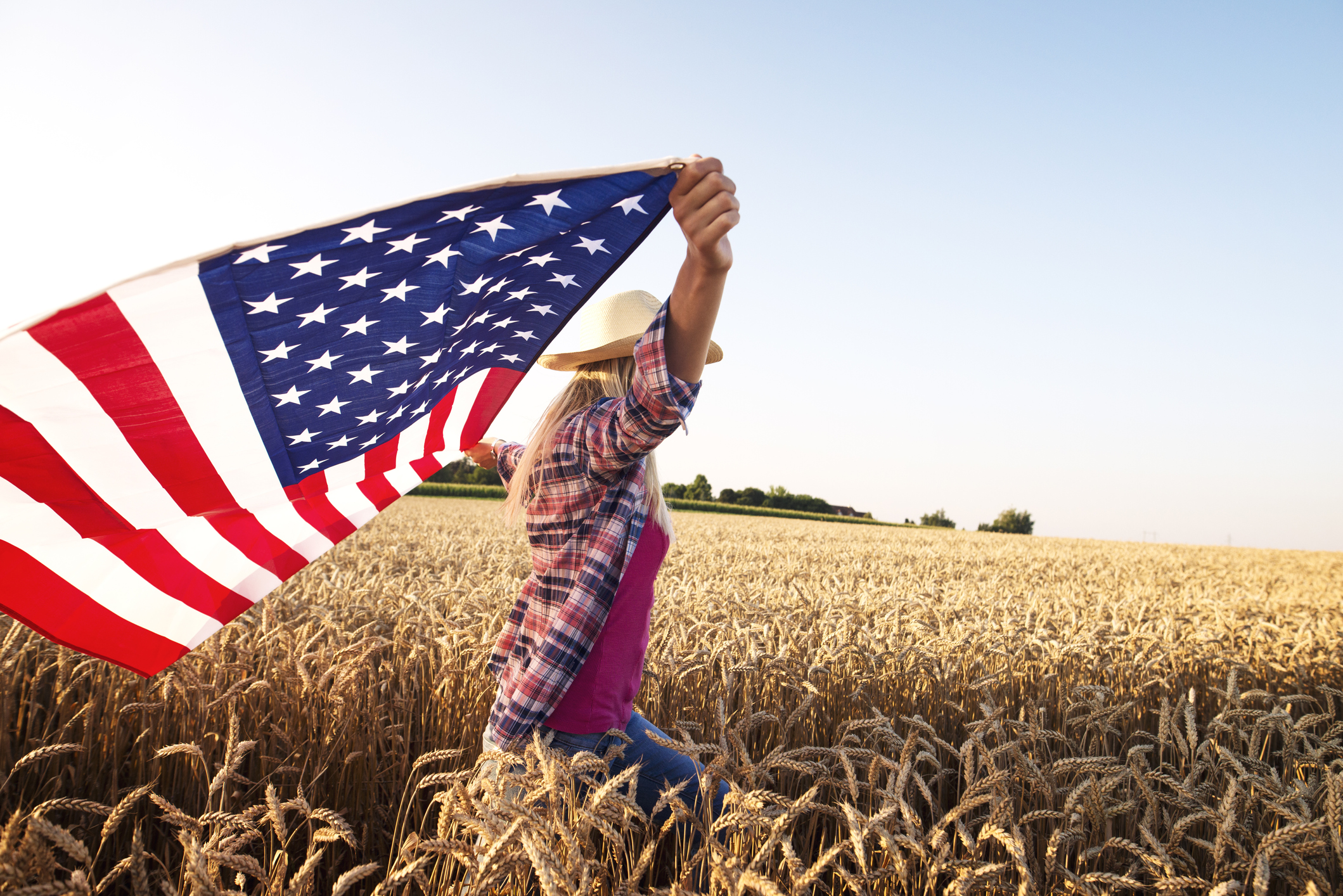 Image of woman holding American flag in a wheat field