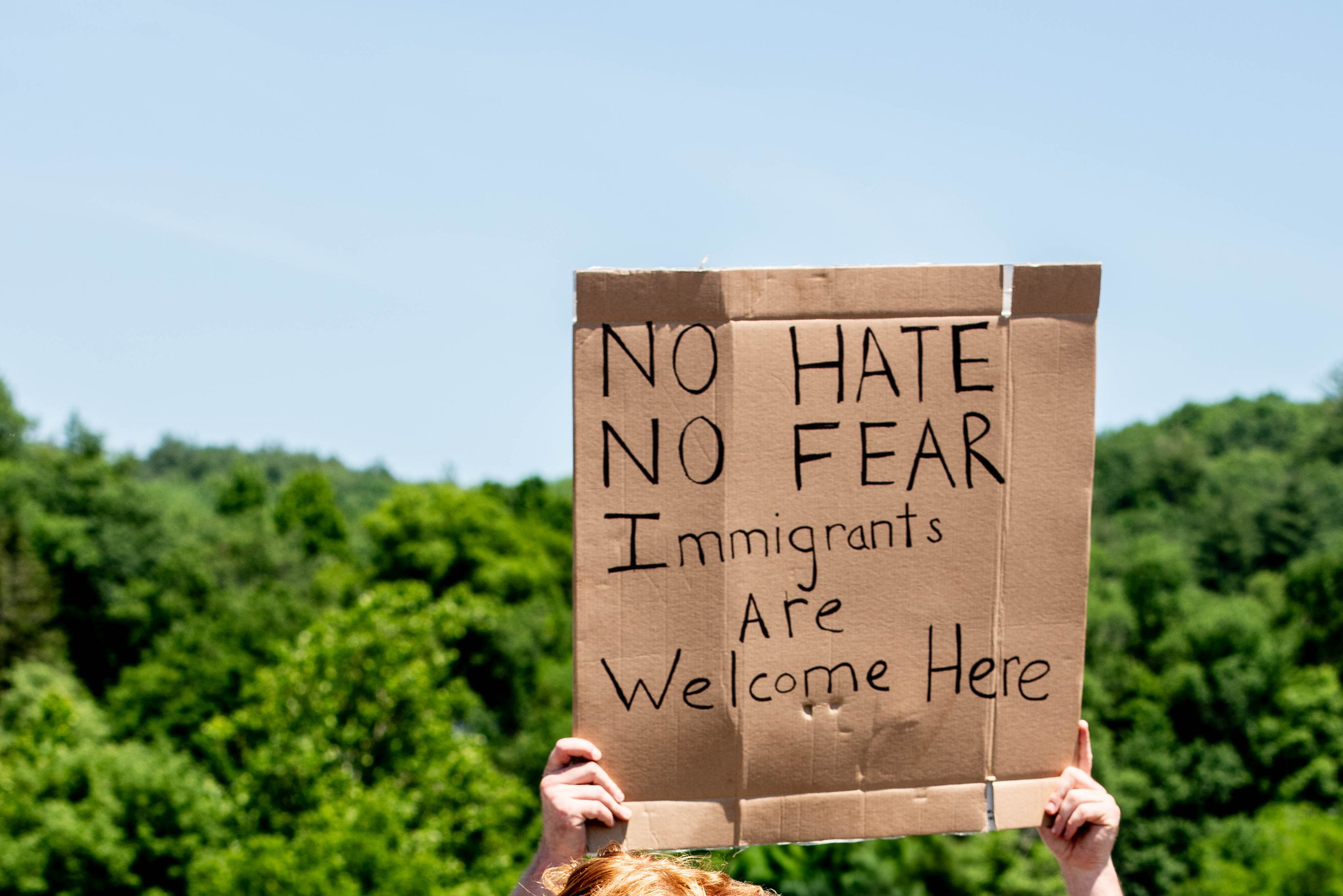 Immigration Protest Sign Reads No Hate, No Fear, Immigrants Are Welcome Here A protestor at a political rally holds a sign that reads "no hate, no fear, immigrants are welcome here."
